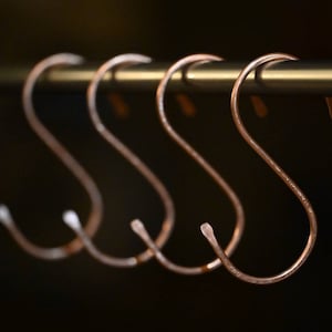 Peut inclure: Quatre crochets en forme de S de couleur cuivre sont suspendus &agrave; une barre m&eacute;tallique. Les crochets sont tous de la m&ecirc;me taille et de la m&ecirc;me forme.