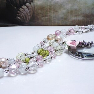 Peut inclure: Un collier multi-rangs avec des perles de verre transparentes, roses et vertes, un pendentif en loupe avec une rose rose et une cha&icirc;ne argent&eacute;e.