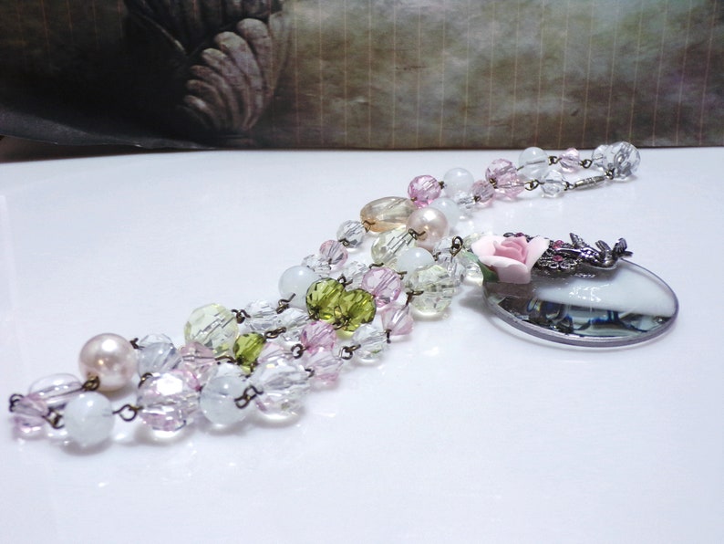 Peut inclure: Un collier multi-rangs avec des perles de verre transparentes, roses et vertes, un pendentif en loupe avec une rose rose et une cha&icirc;ne argent&eacute;e.