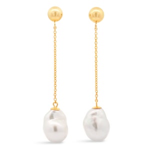 May include: A pair of gold drop earrings with large white baroque pearls. The earrings feature a delicate gold chain and a small gold ball at the top.