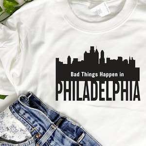 May include: White t-shirt with a black silhouette of the Philadelphia skyline and the text "Bad Things Happen in PHILADELPHIA".