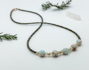 May include: A delicate necklace with a silver chain and five light blue and white agate beads. The beads are separated by small gold beads.