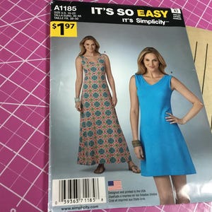 May include: A sewing pattern titled "It's So Easy" by Simplicity, featuring two dress designs. One dress is a long, patterned maxi dress, and the other is a short, solid blue dress. The pattern size is U.S. 10-22.