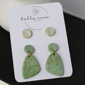 May include: A set of three pairs of earrings featuring green and white speckled clay. The earrings are displayed on a white card with the text "bella rose designs".