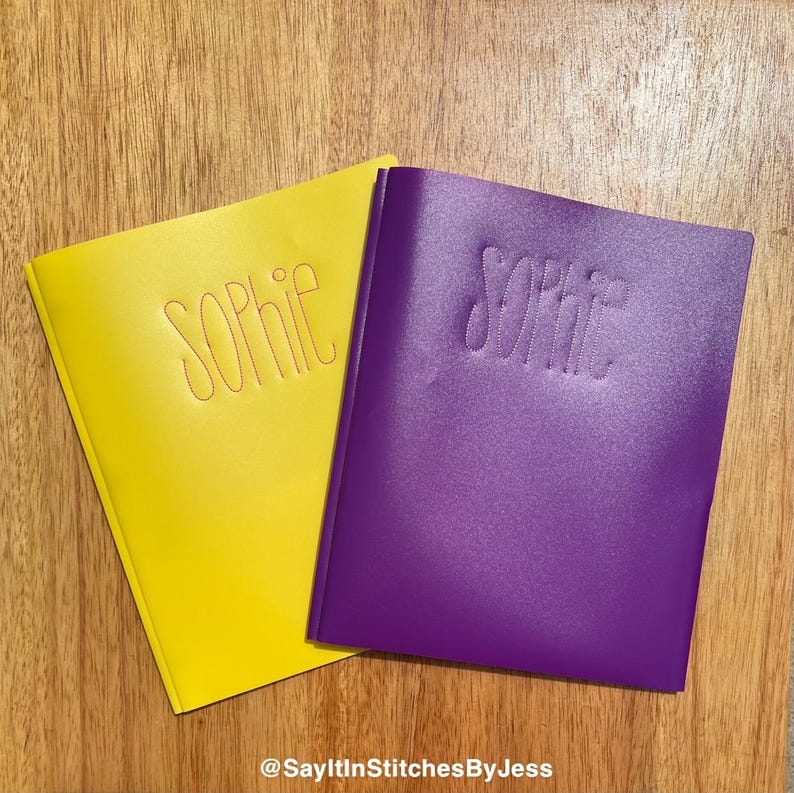 May include: Two personalised folders, one yellow and one purple, with the name "Sophie" embroidered on each in a contrasting colour.