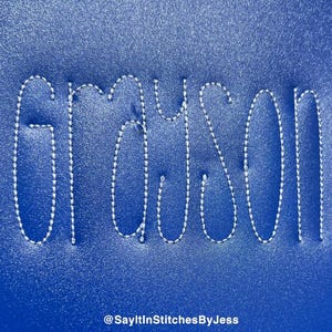 May include: The name "Grayson" is stitched in white thread on a blue background.