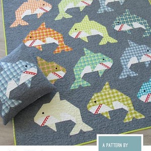 May include: A quilt and pillow pattern titled SOCIAL SHARKS by ELIZABETH HARTMAN. The image displays a dark gray quilt featuring multiple patchwork sharks in various plaid and gingham patterns of orange, green, and blue with white accents.