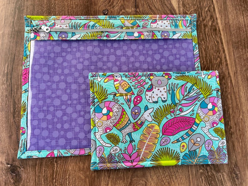 Puede incluir: Dos bolsas de tela con un estampado tropical colorido con tucanes, koalas y otros animales. La bolsa m&aacute;s grande tiene una ventana transparente y cierre de cremallera. La bolsa m&aacute;s peque&ntilde;a es rectangular.