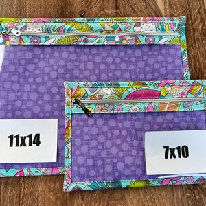 Puede incluir: Dos bolsas con cremallera. La bolsa m&aacute;s grande mide 28x36 cm, y la m&aacute;s peque&ntilde;a 18x25 cm. Ambas tienen un frente transparente, tela morada con lunares y un borde estampado colorido con cremalleras.