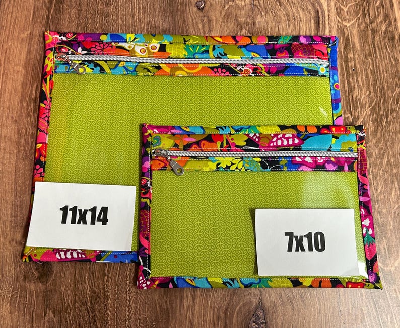 Puede incluir: Dos bolsas transparentes con cremallera y ribete floral colorido. La bolsa m&aacute;s grande mide 28x36 cm, y la m&aacute;s peque&ntilde;a mide 18x25 cm. Ambas tienen un interior verde y una cremallera blanca.