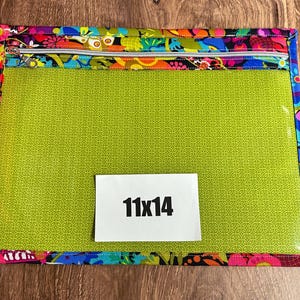 Puede incluir: Bolsa rectangular con un borde floral colorido y una cremallera plateada. El centro es verde lima y transparente. Una etiqueta blanca muestra "11x14".