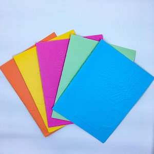 May include: Five colorful blank cards with embossed designs. The cards are arranged in a fan shape, with the blue card on top and the orange card on the bottom.