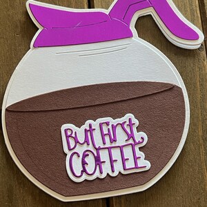 May include: A brown and white coffee pot with a purple lid and handle. The coffee pot has the text "But First Coffee" written on it.