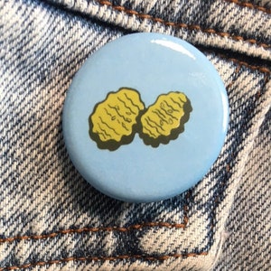 May include: A blue button with a white background and a yellow image of two fried chicken nuggets.