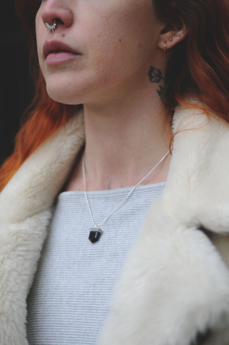A small black onyx crystal necklace on a model’s neck.