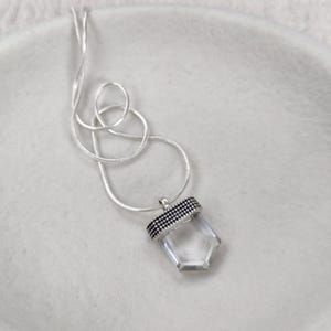 Silver necklace with a clear quartz pendant adorned with dotted details.
