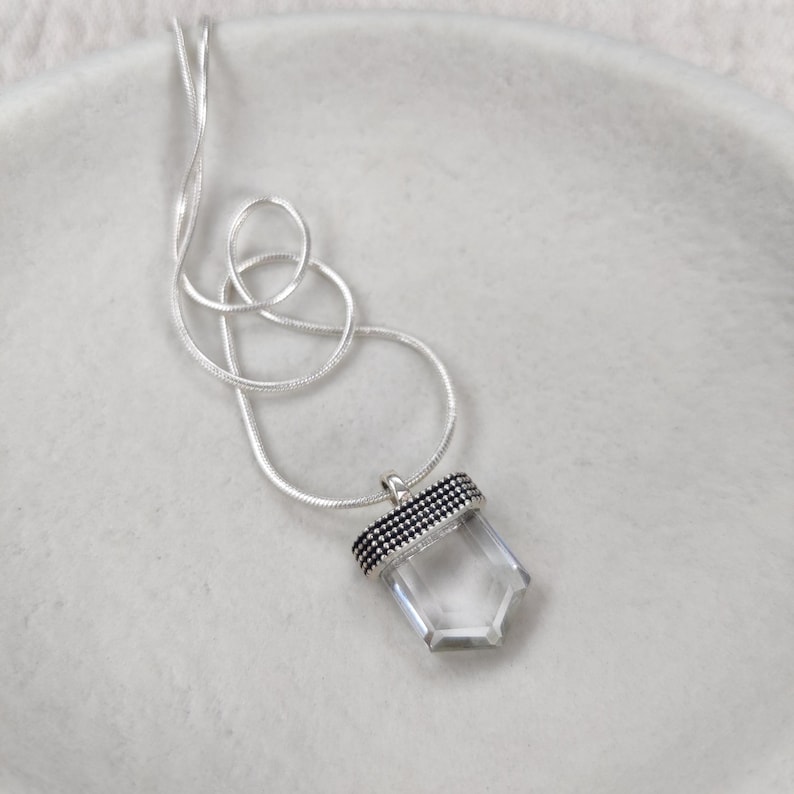Silver necklace with a clear quartz pendant adorned with dotted details.