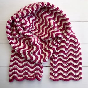May include: A pink and white crocheted scarf with a wavy pattern.