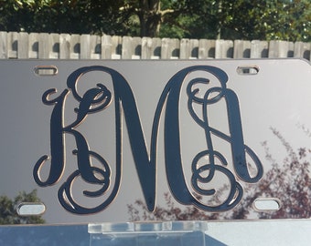May include: A black and silver personalized license plate with the monogram "KMA" in a decorative script font.