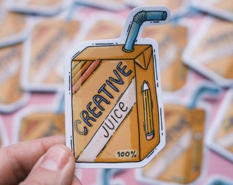 May include: A sticker of a cartoon juice carton with a straw and a pencil sticking out of it. The juice carton is orange and has the words "Creative Juice" and "100%" on it.