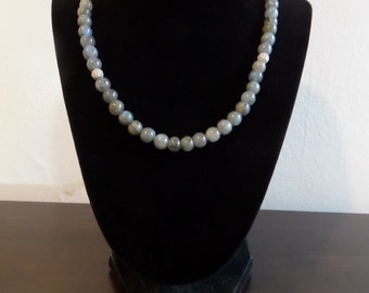 May include: A gray gemstone necklace with silver accents. The necklace is displayed on a black velvet mannequin bust.
