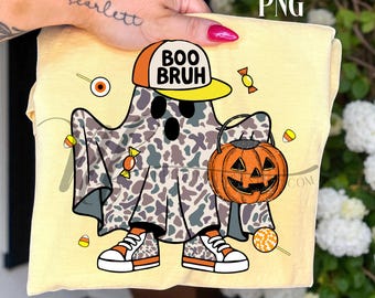 Op de afbeelding: Lichtgeel T-shirt met een cartoongeest in een camouflage laken, met een pet met de tekst "BOO BRUH". De geest houdt een pompoen-lantaarn-emmer vast en draagt sneakers. Snoepjes liggen verspreid rond de geest.