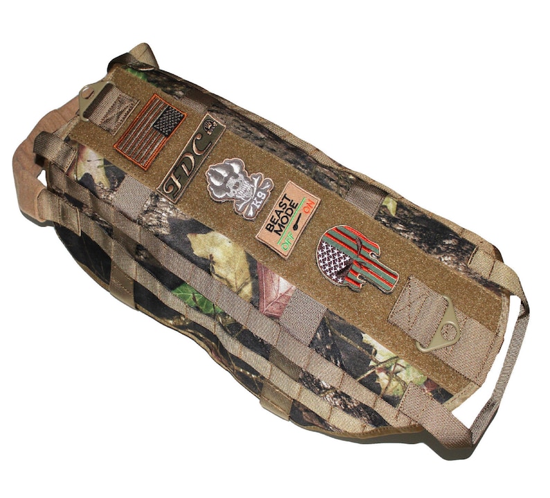 May include: A camouflage dog harness with multiple patches, including an American flag, a skull and crossbones, and a patch that says "Beast Mode".