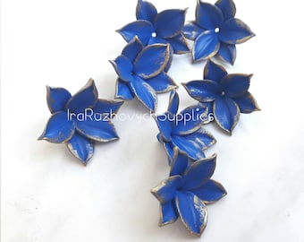 May include: Six blue flower embellishments with gold accents. The flowers have five petals each and are made of a textured material.