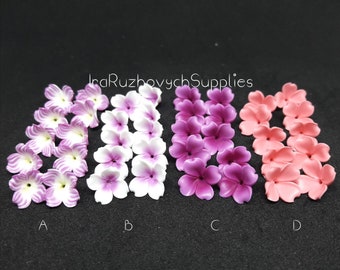 May include: Four rows of polymer clay flower embellishments in different colours. The top row is purple, the second row is white with purple centres, the third row is pink, and the bottom row is light pink.