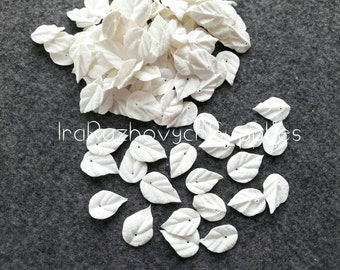 May include: A pile of white paper leaves with a hole in the center of each leaf. The leaves are scattered on a gray surface.