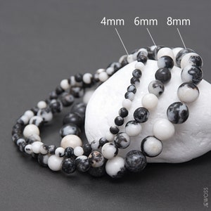 May include: Three strands of black and white gemstone beads, each with a different size: 4mm, 6mm, and 8mm. The beads are round and have a speckled pattern.