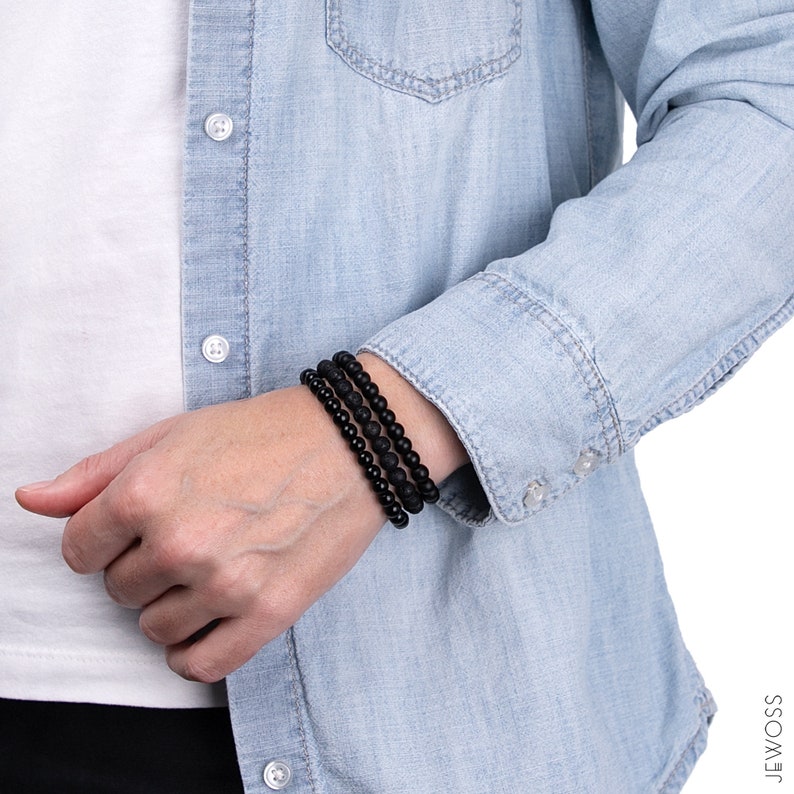 May include: A set of three black beaded bracelets stacked on a person's wrist. The bracelets are made of small, round beads.