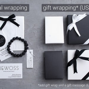 May include: Two options for wrapping a gift: a white paper bag with a black ribbon and a black and white gift box with a white ribbon. The gift box is available for an additional $3. The image also includes a black lava rock bracelet and a business card with the text "JEWOSS" on it.