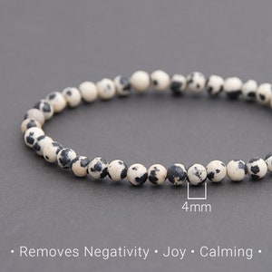Puede incluir: Un brazalete hecho de cuentas de jaspe dalmata blanco y negro, cada cuenta mide 4 mm de diámetro.  Elimina la negatividad. Alegría. Calmante.