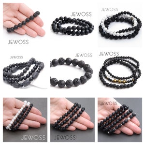 May include: Set of three black lava stone bracelets. The bracelets are made of round beads with a rough, textured surface. The bracelets are stacked on top of each other.