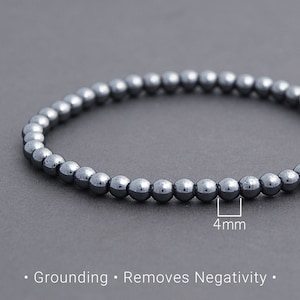 May include: A black hematite beaded bracelet with 4 mm beads. The bracelet is made of natural hematite stones, known for their grounding and protective properties.