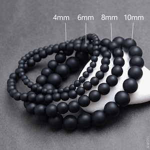 Puede incluir: Cuatro pulseras de cuentas negras con cuentas de diferentes tamaños. Las cuentas tienen un diámetro de 4 mm, 6 mm, 8 mm y 10 mm.