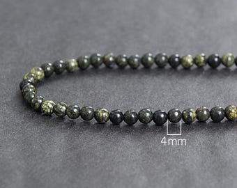 Könnte beinhalten: Ein grünes und schwarzes Perlenarmband mit 4 mm Perlen. Das Armband ist aus Naturstein gefertigt und für Meditation, Liebe und Fülle gedacht.