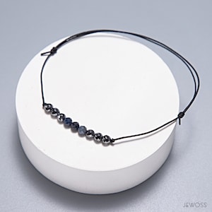 May include: A black string bracelet with a row of dark blue and silver beads.