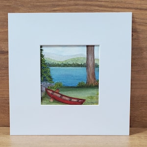 May include: A watercolor painting of a red canoe resting on the shore of a lake. The lake is surrounded by green trees and hills. The painting is signed "D. Santiago 2019".