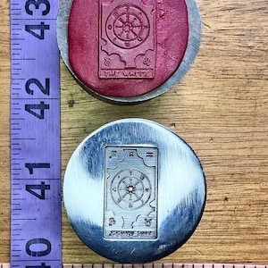 Collezione di tarocchi con matrice in acciaio raffigurante il matto, l'eremita e la ruota della fortuna.