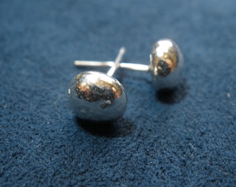 Op de afbeelding: Een paar zilveren oorbel studs met een getextureerde, gehamerde afwerking. De oorbellen zijn rond en hebben een licht onregelmatige vorm.