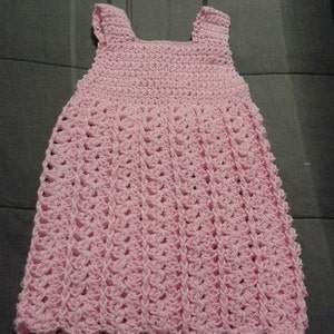 May include: A pink crocheted sleeveless dress with a scalloped hem.