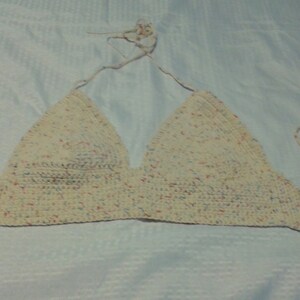 Puede incluir: Un top halter blanco de ganchillo con un patr&oacute;n moteado de rosa, azul y amarillo.