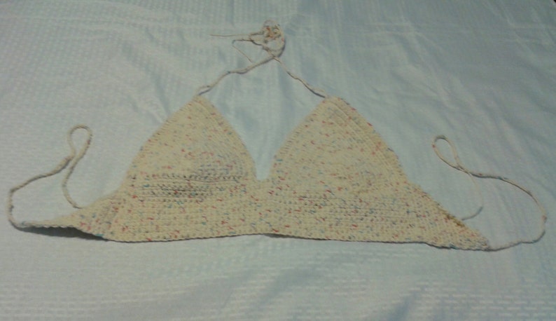 Puede incluir: Un top halter blanco de ganchillo con un patr&oacute;n moteado de rosa, azul y amarillo.