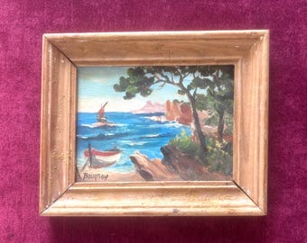 Peinture à l'huile des années 1930 représentant des bateaux et des rochers rouges sur la Côte d'Azur. Art ancien méditerranéen signé Bourbon. Petit format encadré.