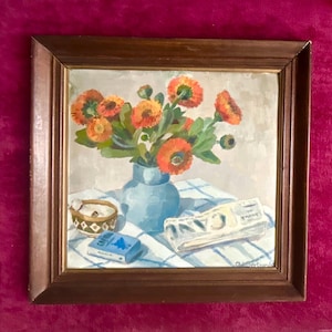 Pintura al óleo francesa sobre cartón, década de 1940. Bodegón con periódico, cigarrillos y jarrón de zinnias anaranjadas. Arte floral. Decoración floral.