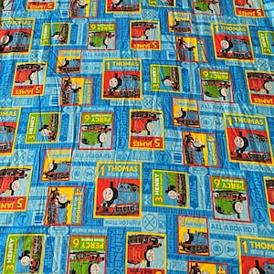 May include: Blue fabric with a repeating pattern of Thomas the Tank Engine and friends. The design includes images of Thomas, James, Henry, Percy, and Gordon, with the text "Thomas Blue Engine" and "All Aboard".