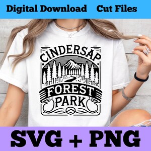 May include: White t-shirt with a black graphic design that says "Cindersap Forest Park" with a mountain and trees in the design.