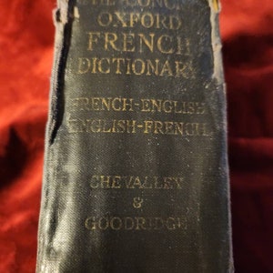 May include: A black, worn, hardcover book titled "The Concise Oxford French Dictionary, French-English & English-French, Chevalley & Goodrich".